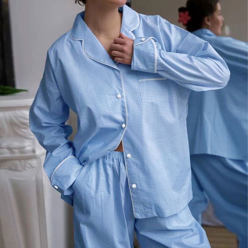 Person wearing a blue checkered pajama set in a neutral setting